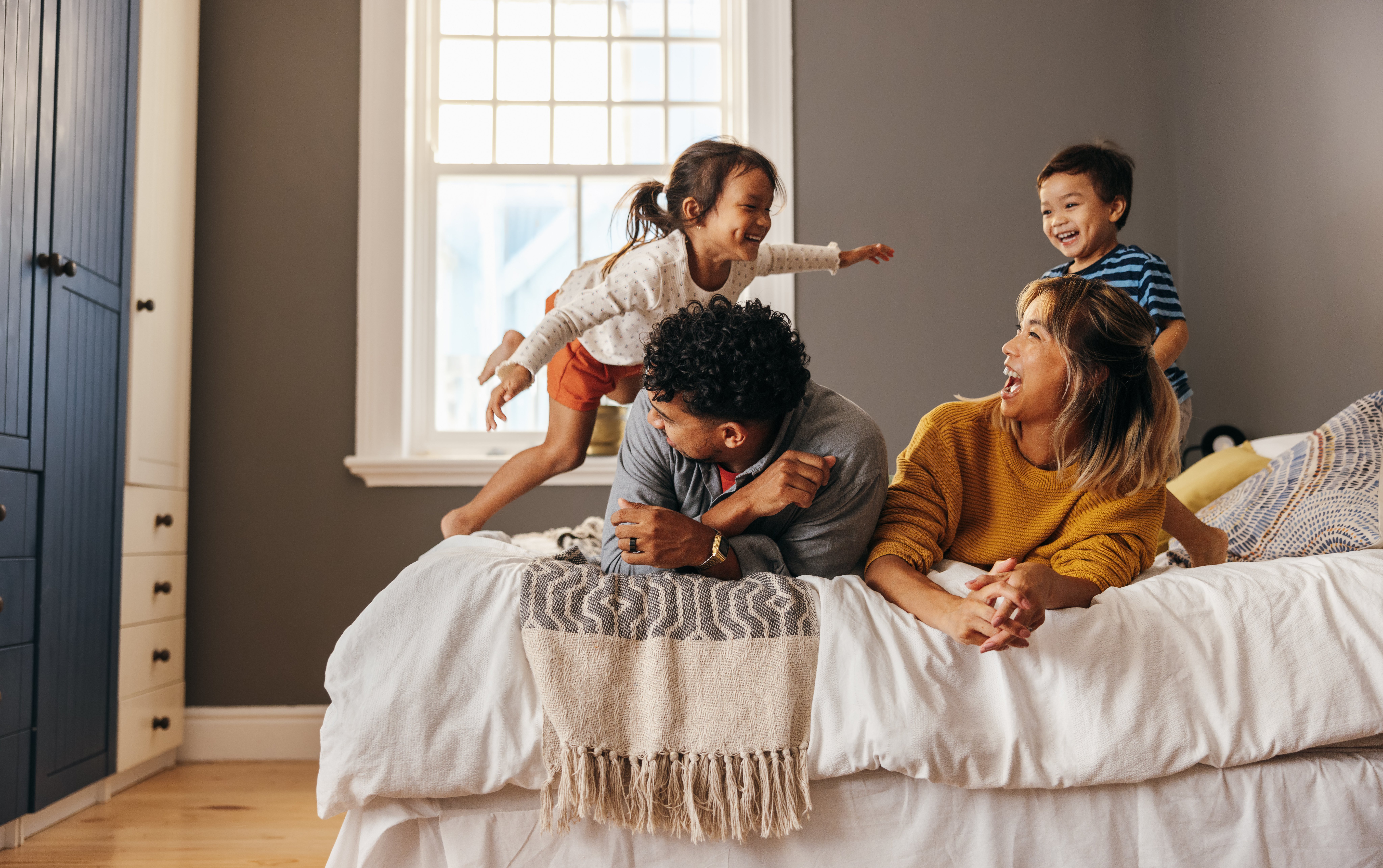 Happy family laughing and having fun together on the bed